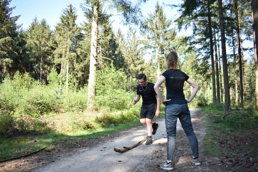 Trainer geeft sporttraining in het bos aan één klant. 