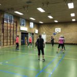 Dames spelen volleybal in een gymzaal